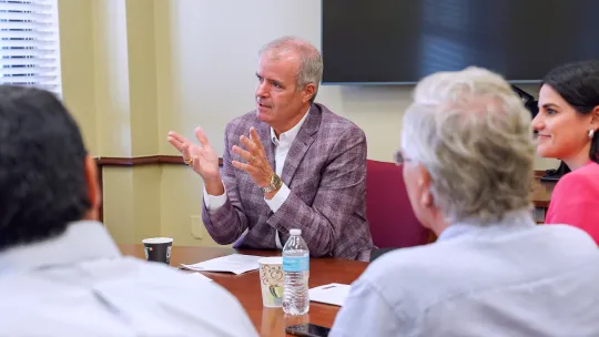 Provost in a meeting with three others sitting at a table