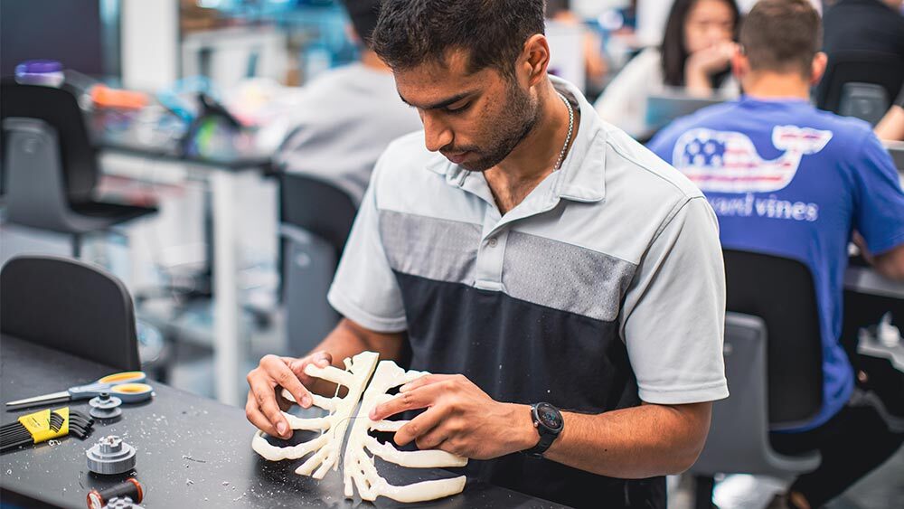 A student grips a prototype of a rib cage.